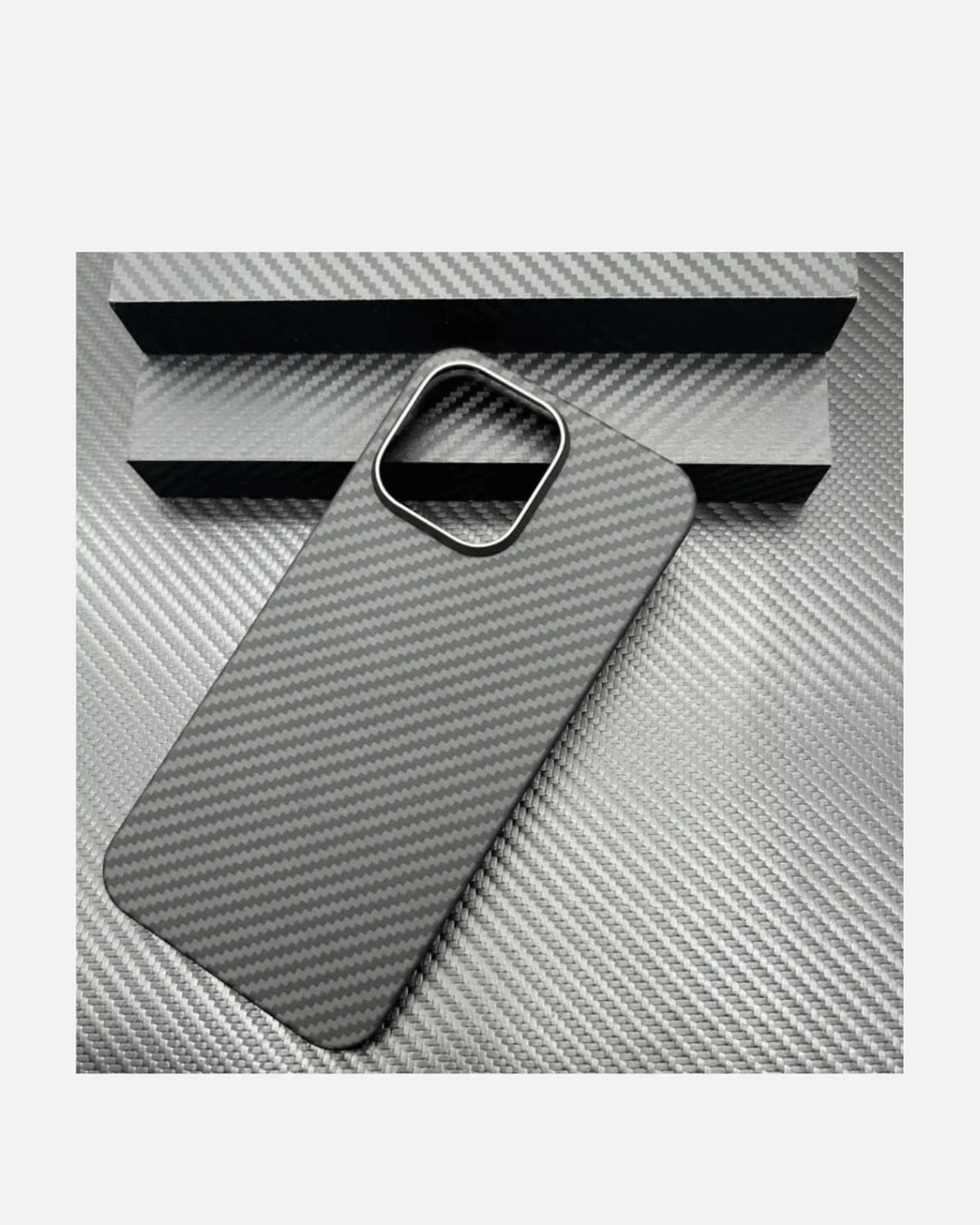 Ultra-thin aramid fiber iPhone case with metal camera frame on textured gray surface.