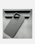 Ultra-thin aramid fiber iPhone case with metal camera frame on textured gray surface.