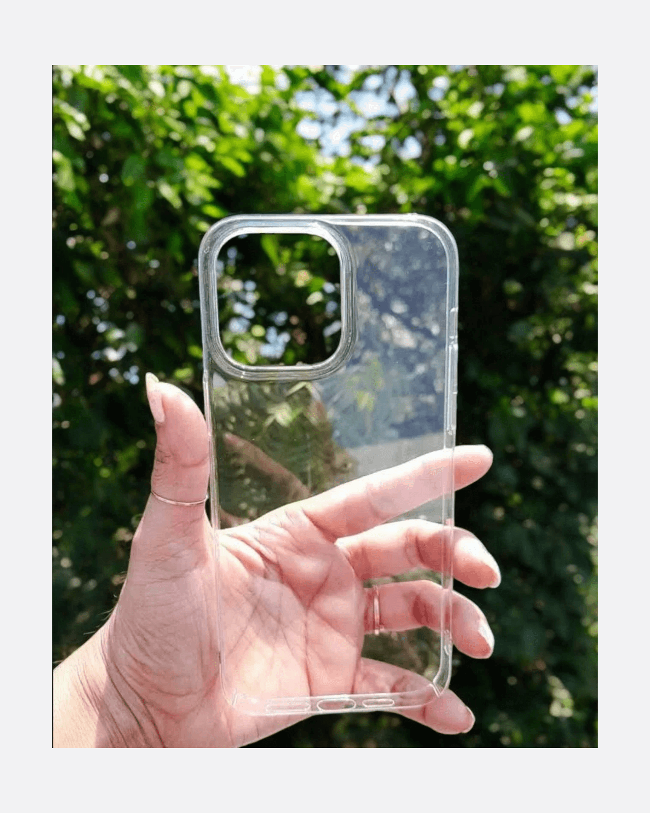 Hand holding an ultra slim transparent iPhone case with a clear back against a green background.